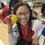 A girl holding a toy and smiling at the photographer