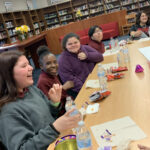 A group of five girls seated at a table in a library