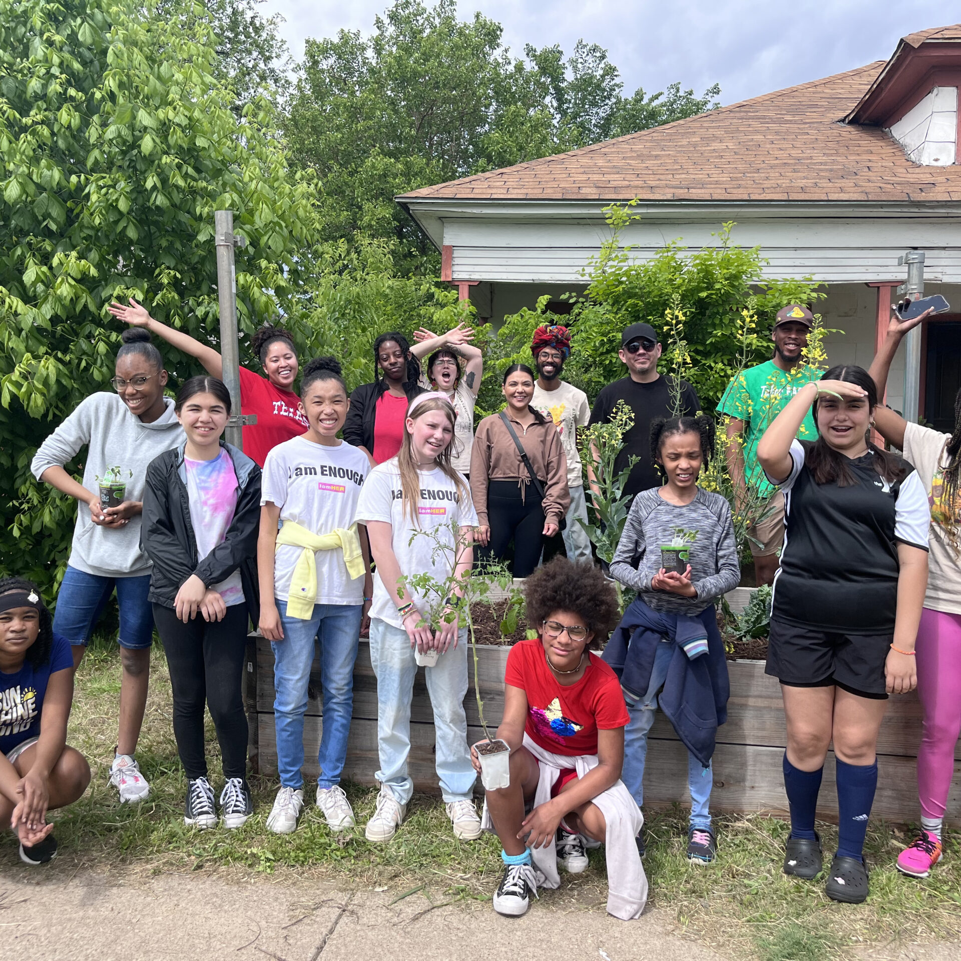 A group of girls and volunteers standing and smiling at the photographer